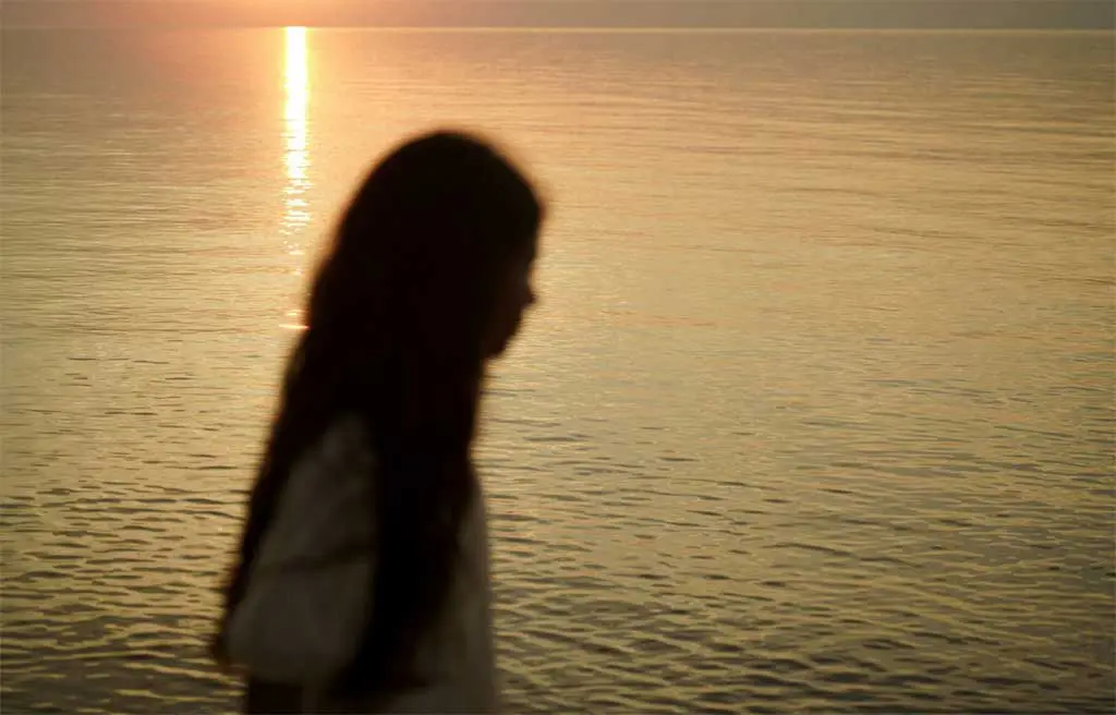 girl walking near ocean at sunset