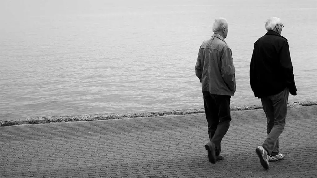 two elderly men walking near river