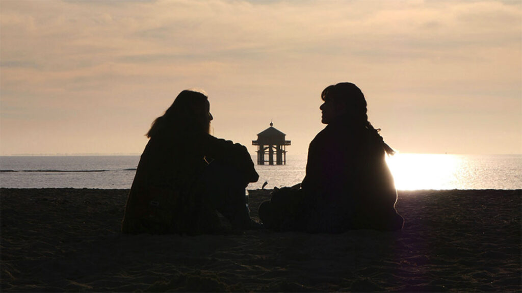 people talking on a beach at sunset